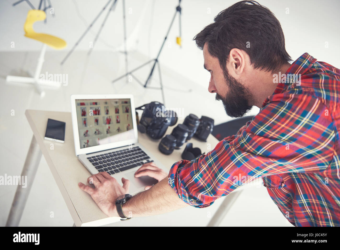 Male photographer reviewing photo shoot on laptop in studio Stock Photo