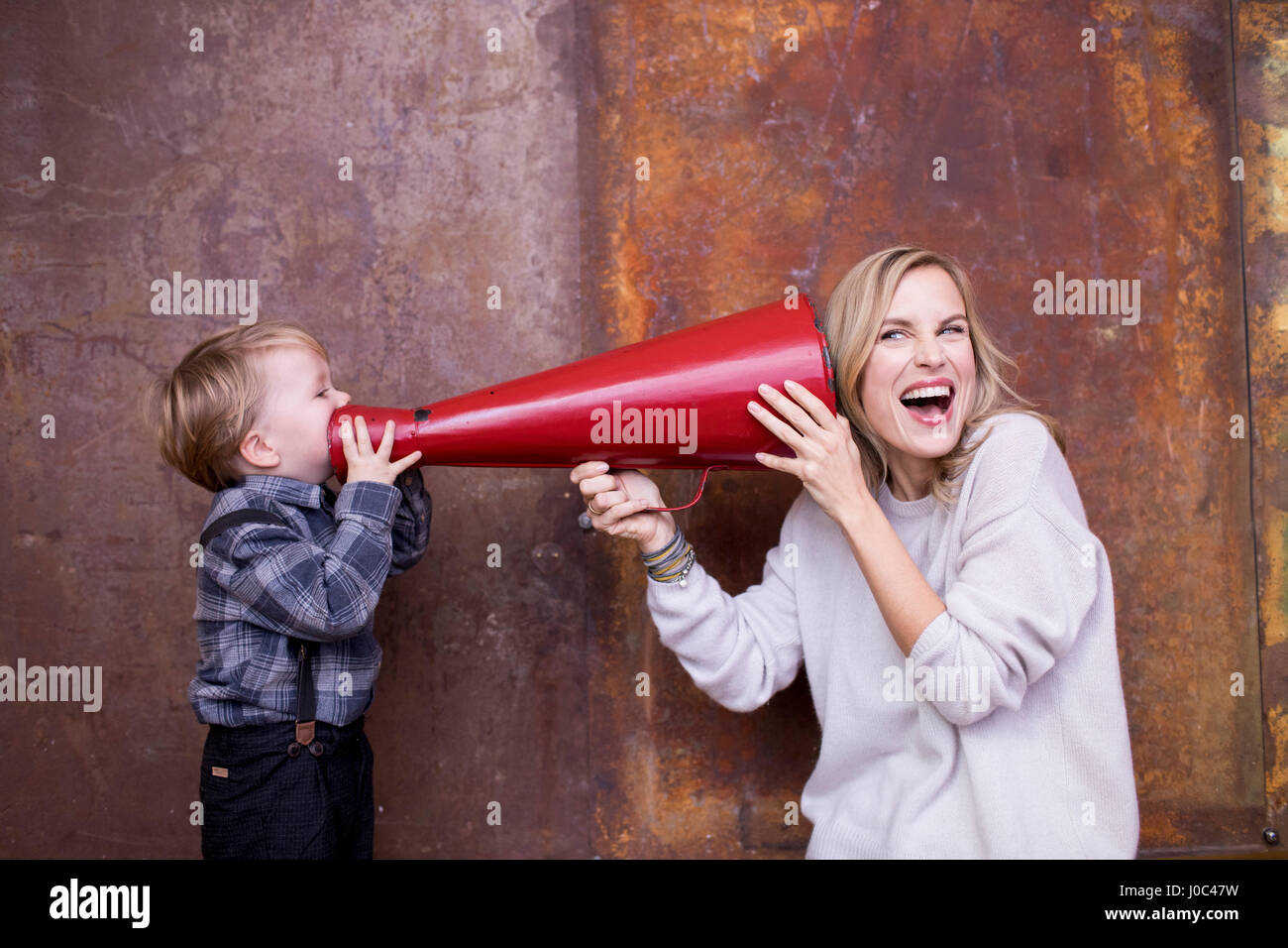 Young boy speaking into megaphone, woman holding megaphone to her ear Stock Photo