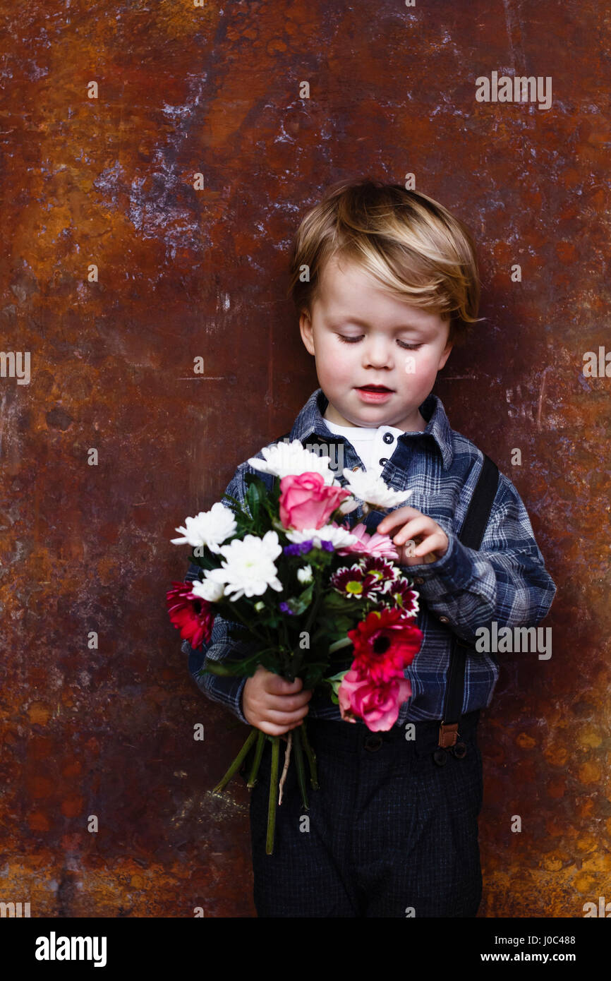 Young boy holding bunch of flowers Stock Photo
