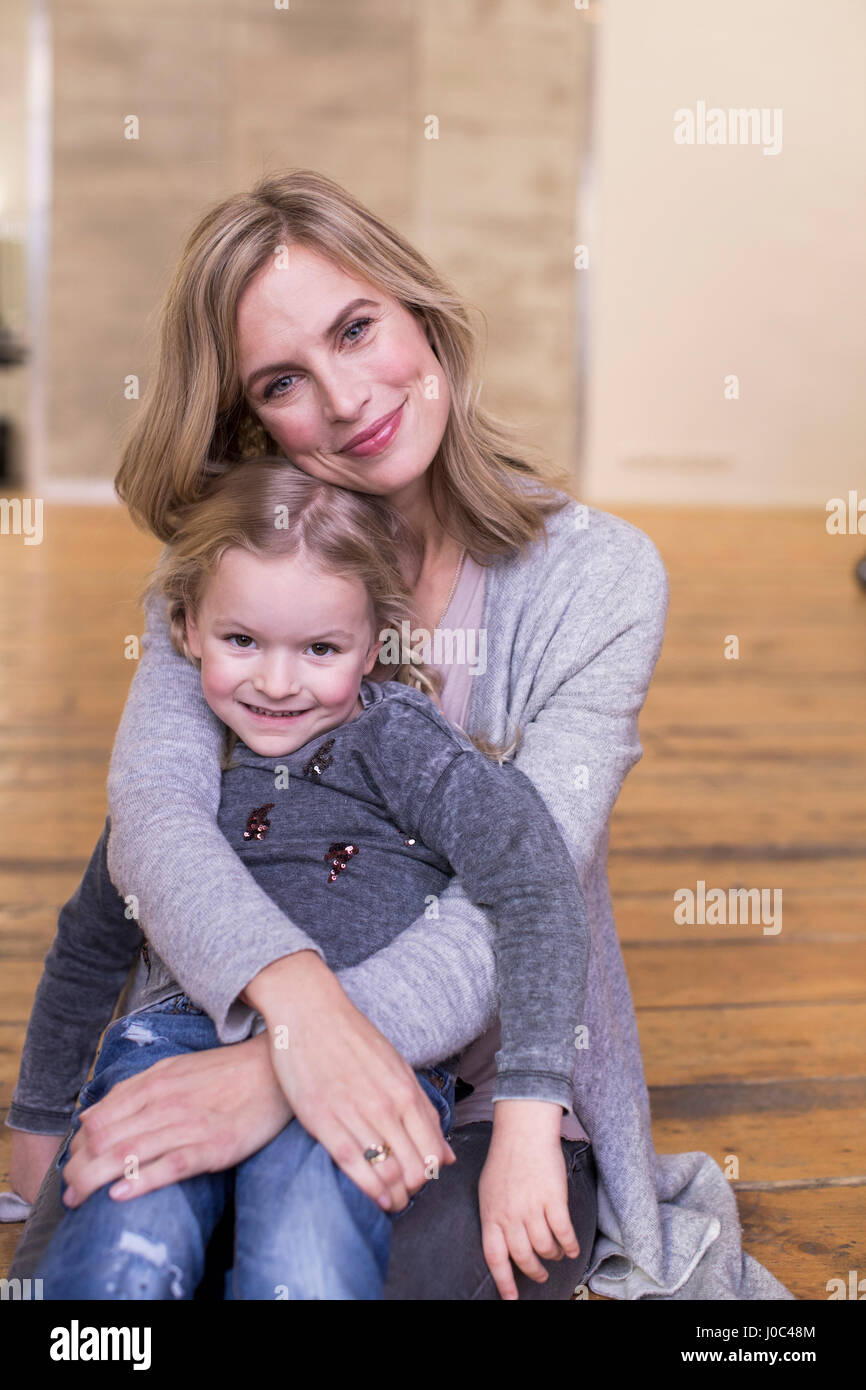 Portrait of mother and daughter, sitting on floor, smiling Stock Photo