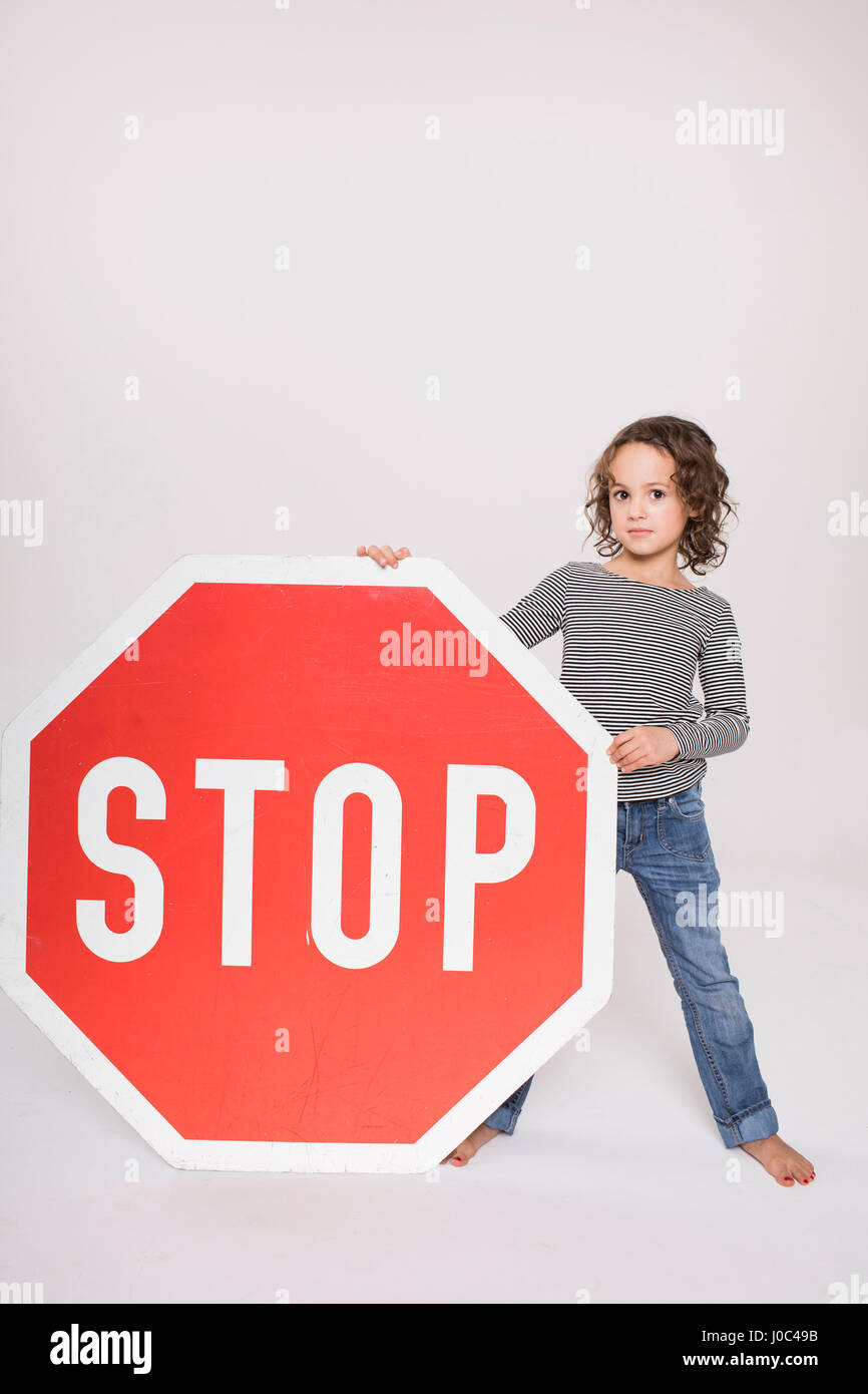 Portrait of young girl, holding giant stop sign Stock Photo