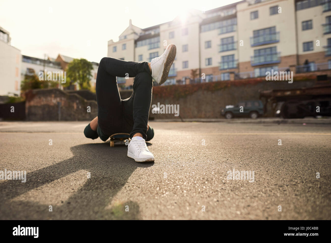Young man laying on skateboard, relaxing, Bristol, UK Stock Photo