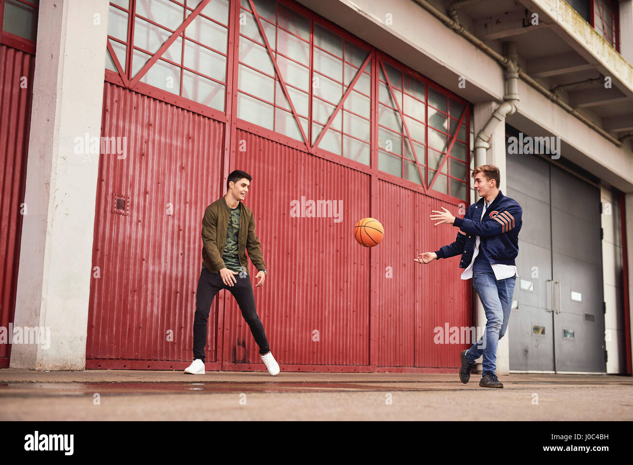 Two young men playing basketball in urban area, Bristol, UK Stock Photo
