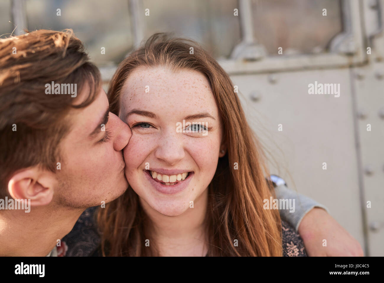 Young man kissing young woman on cheek, Bristol, UK Stock Photo