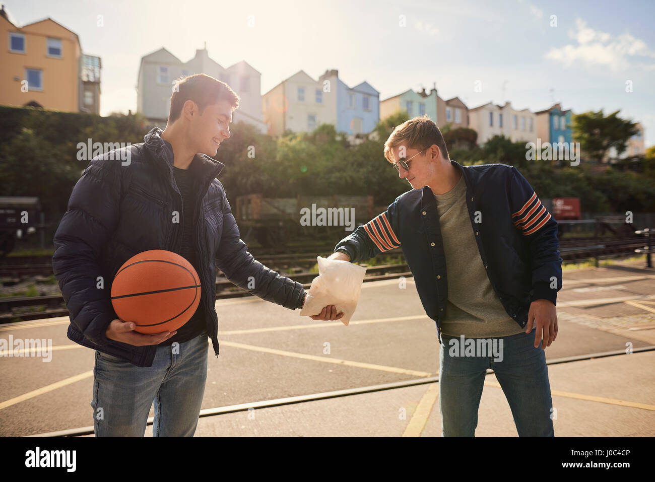 Young man sharing bag of chips with friend, young man holding basketball, Bristol, UK Stock Photo