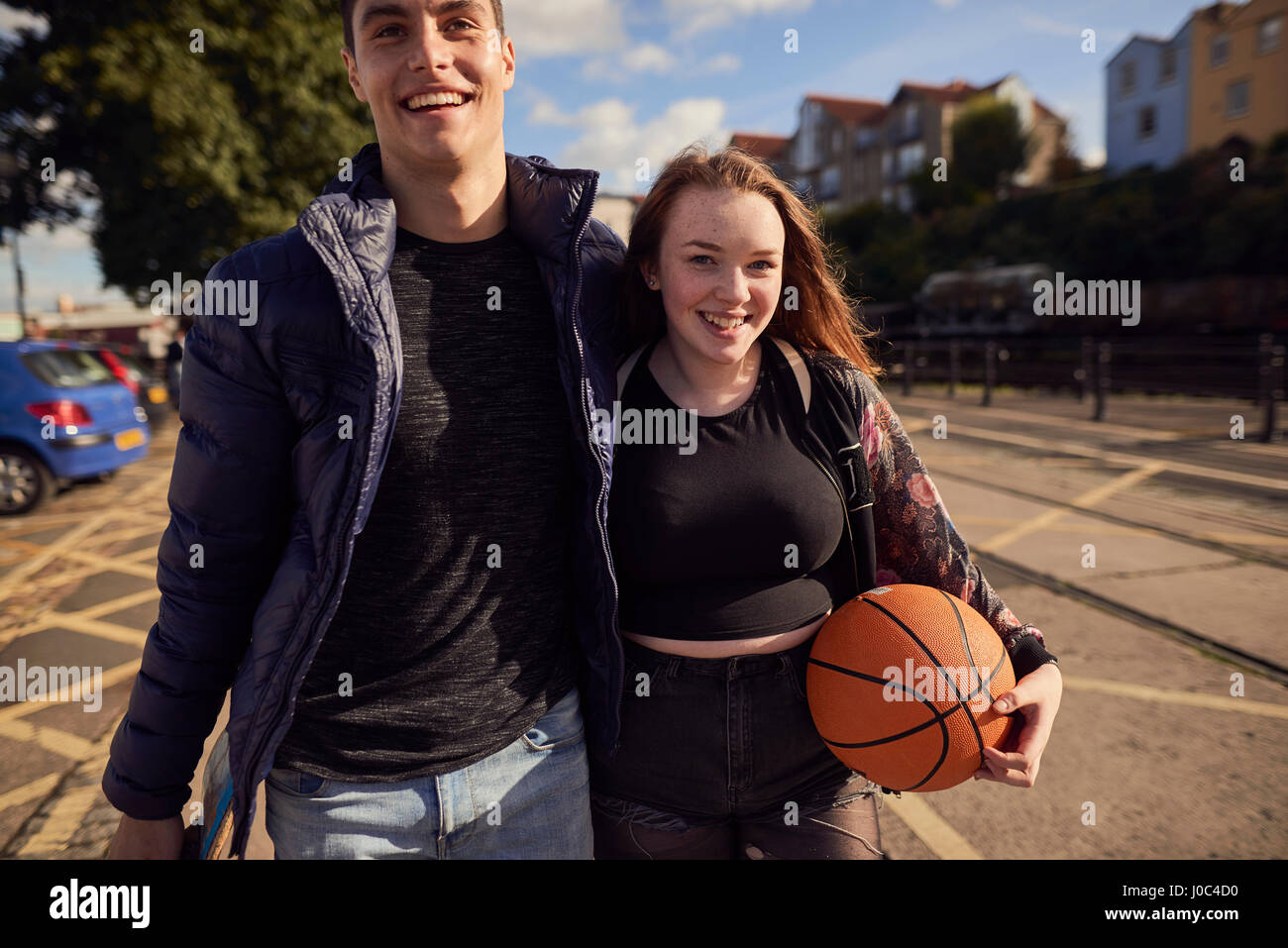 Two friends walking outdoors, young woman holding basketball, Bristol, UK Stock Photo