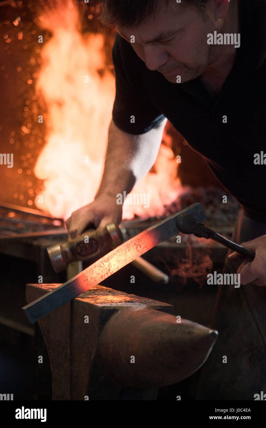Farrier forging horseshoe on anvil Stock Photo