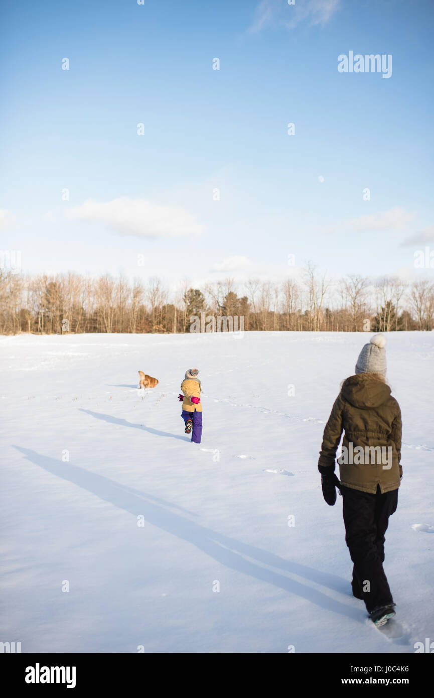 Kids and dogs playing in snow-covered field, Lakefield, Ontario, Canada Stock Photo