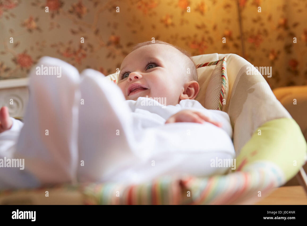 Baby girl lying on baby bouncer chair in nursery Stock Photo Alamy