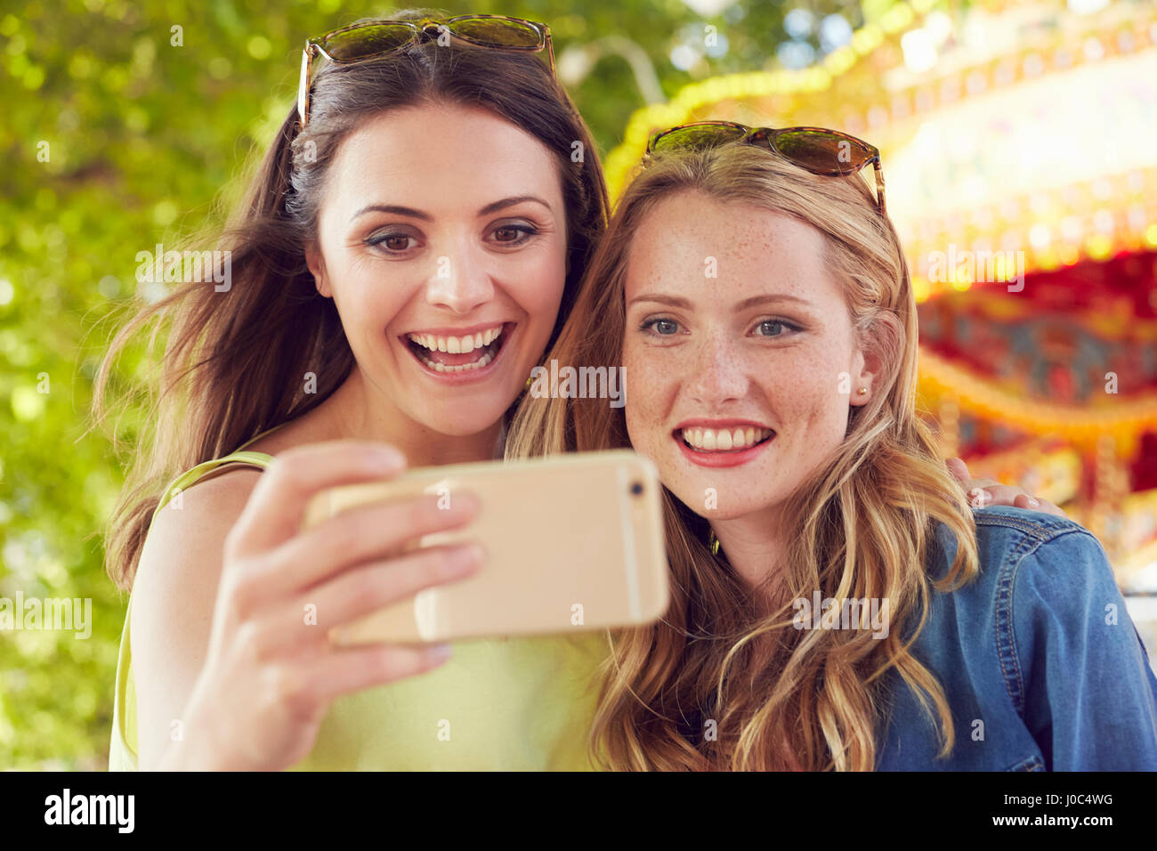 Women taking selfie, carousel in background, London, UK Stock Photo