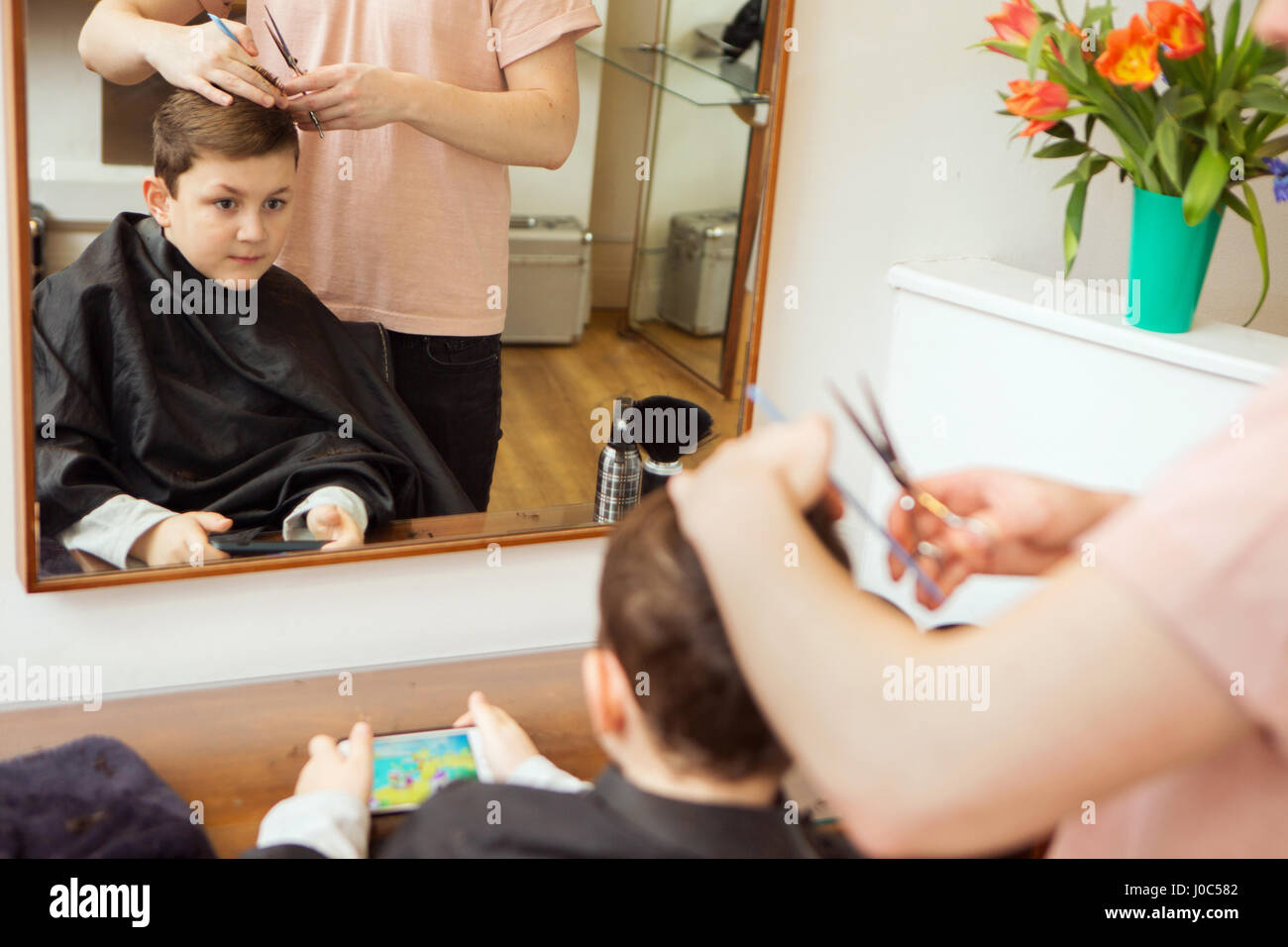 Male hairdresser trimming boy's hair in hair salon Stock Photo
