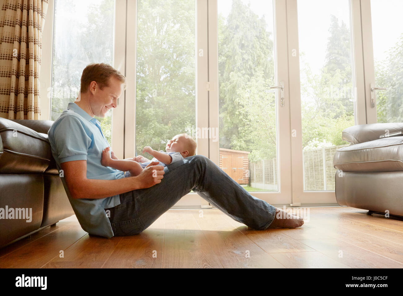 Mature man sitting on floor with baby son on his lap Stock Photo