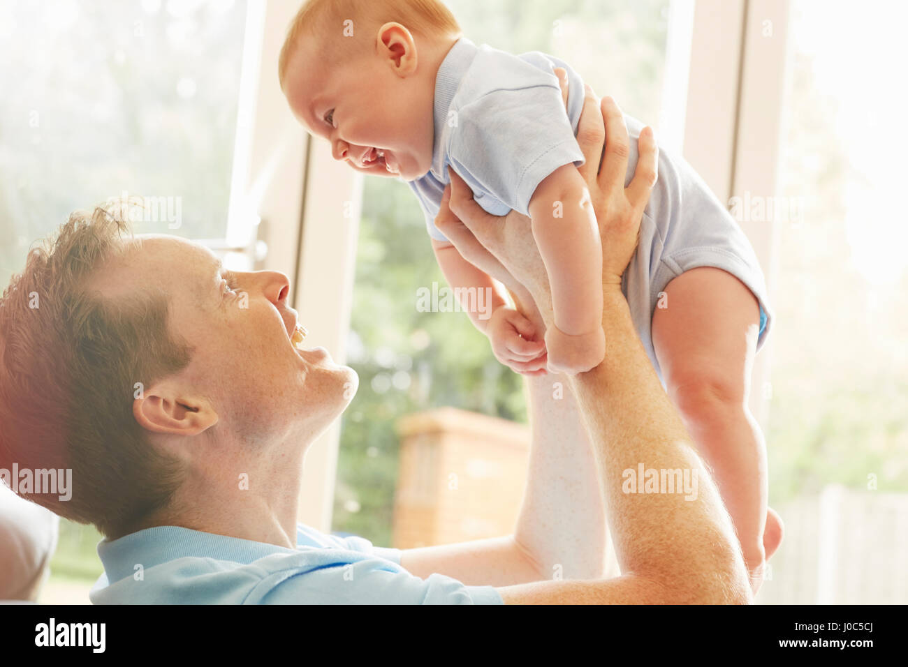 Mature man holding up baby son Stock Photo