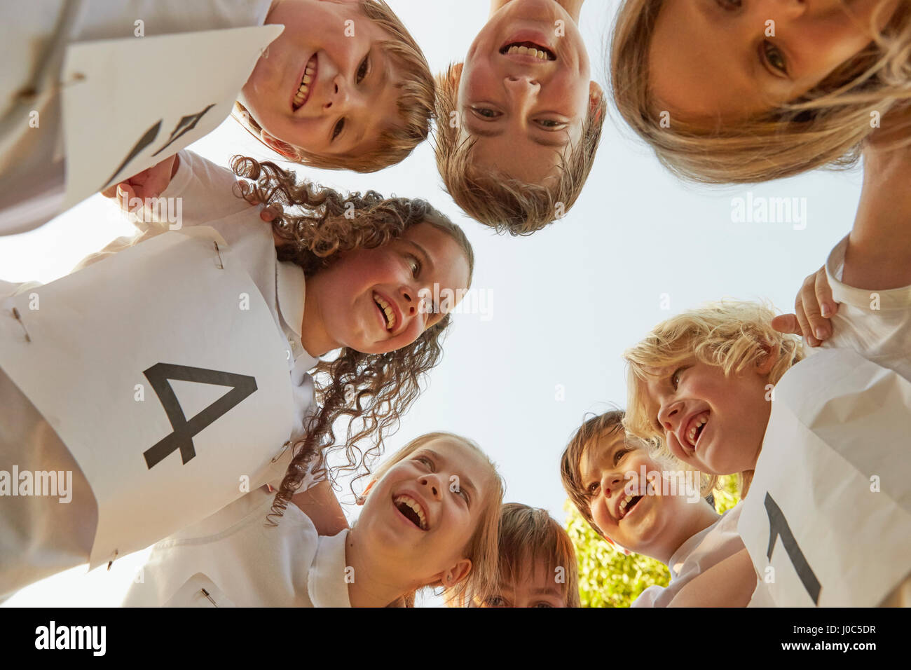 Low angle view of boy and girl sport team huddled in circle Stock Photo