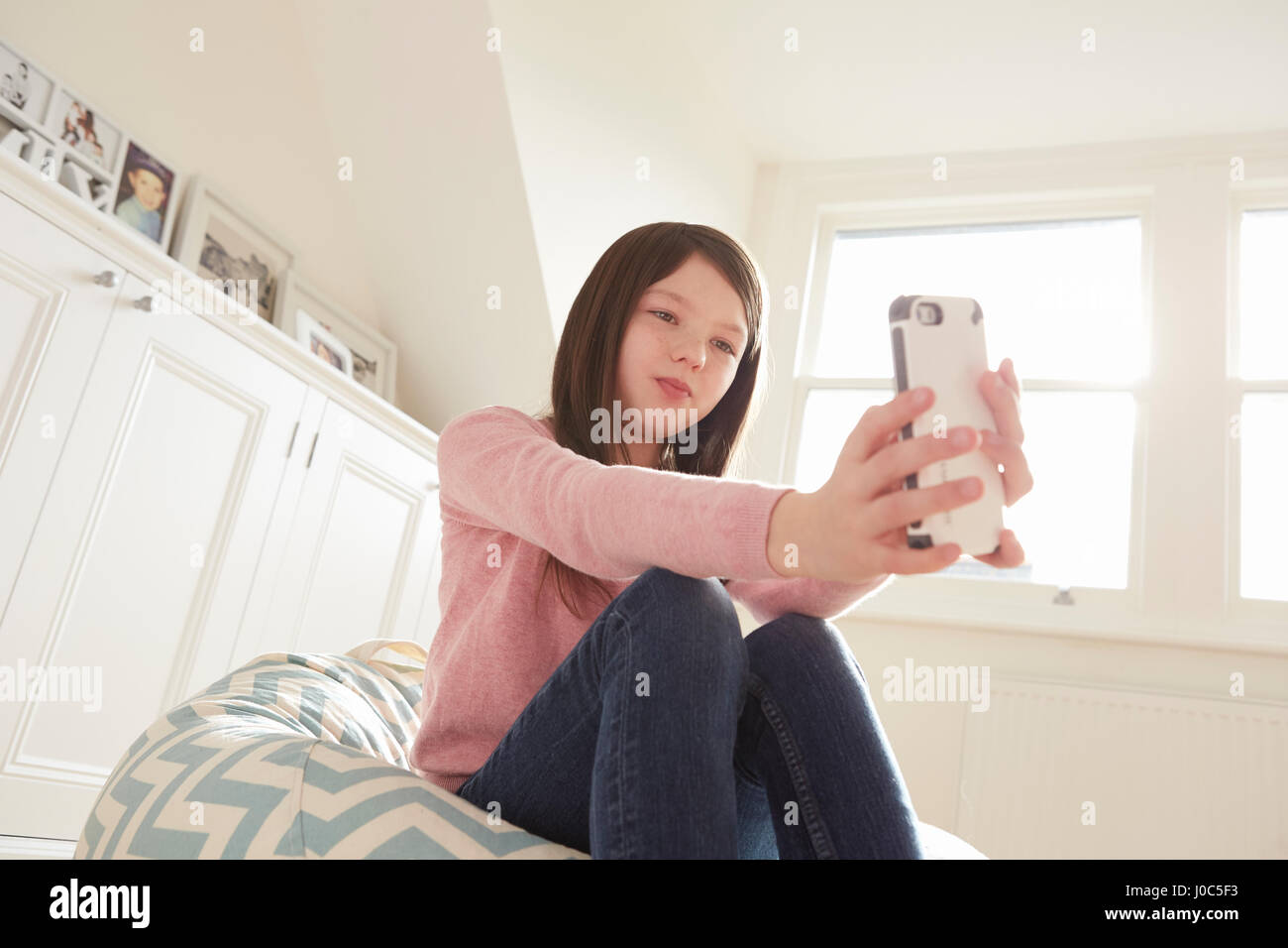 Girl sitting on beanbag chair taking smartphone selfie Stock Photo - Alamy