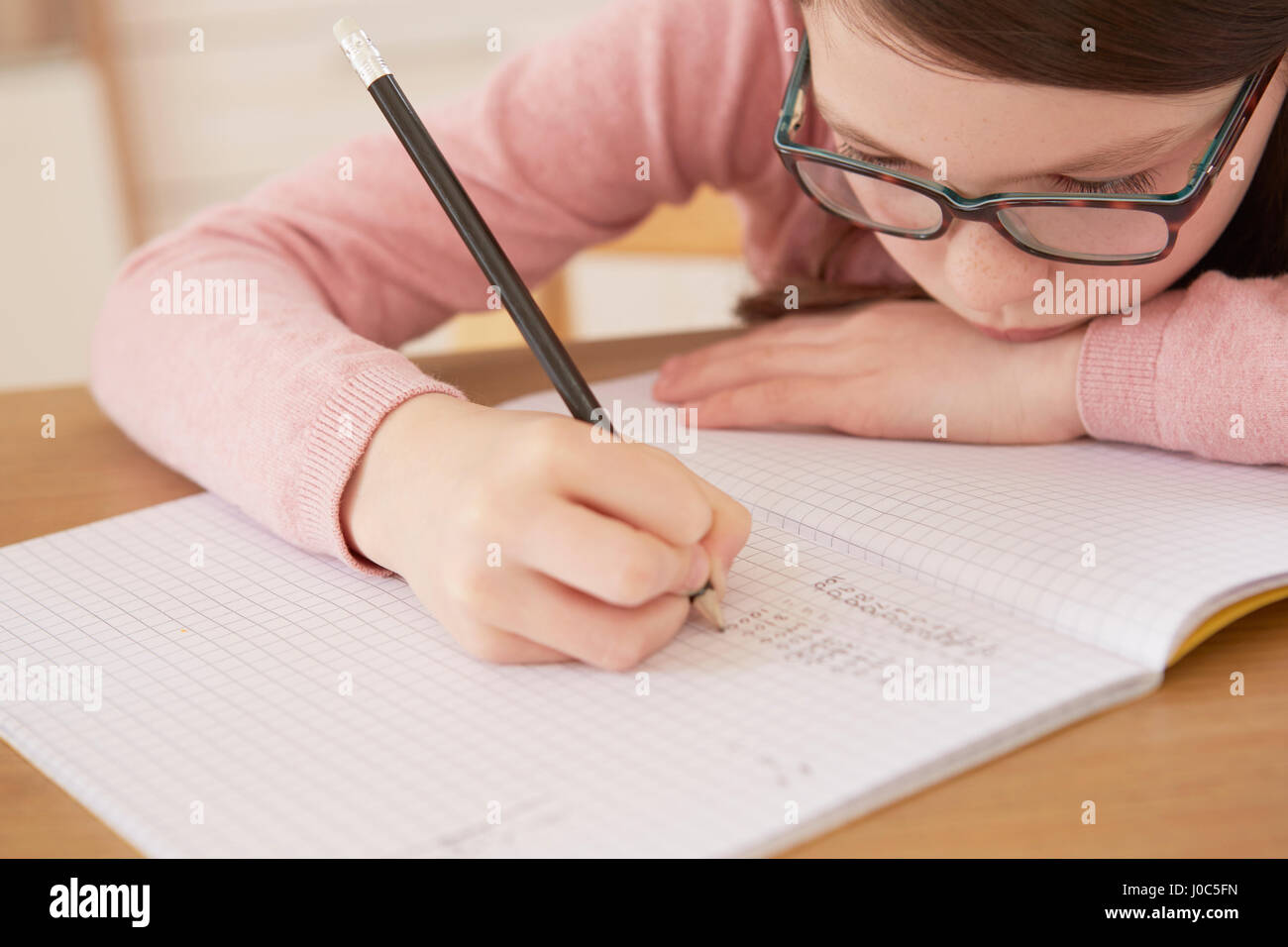 Close up of girl doing homework at table Stock Photo