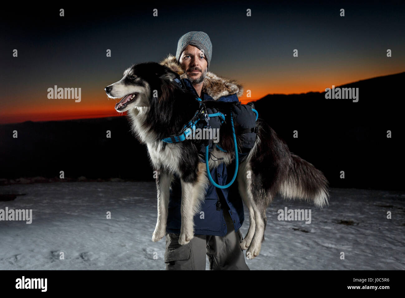 Portrait of mature man carrying dog in snow at night Stock Photo