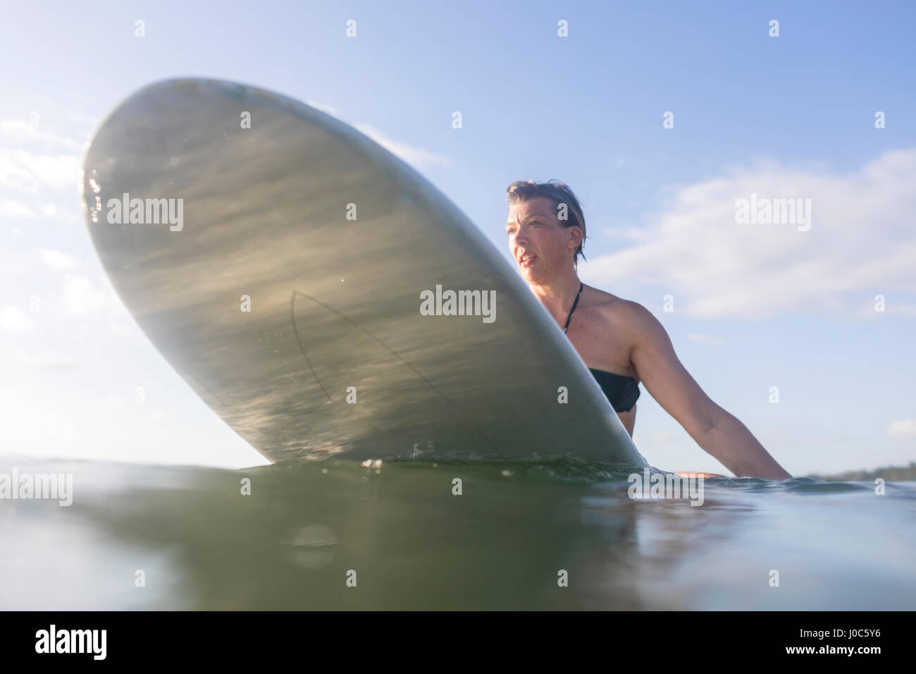 Woman straddling surfboard in sea, Nosara, Guanacaste Province, Costa Rica Stock Photo