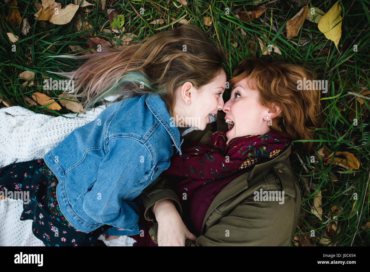Mother and daughter lying on grass making funny faces Stock Photo