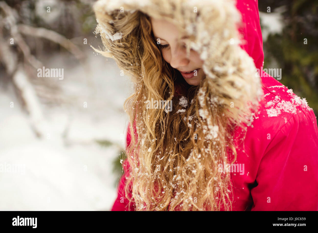 Girl in parka with snow in her hair looking down Stock Photo