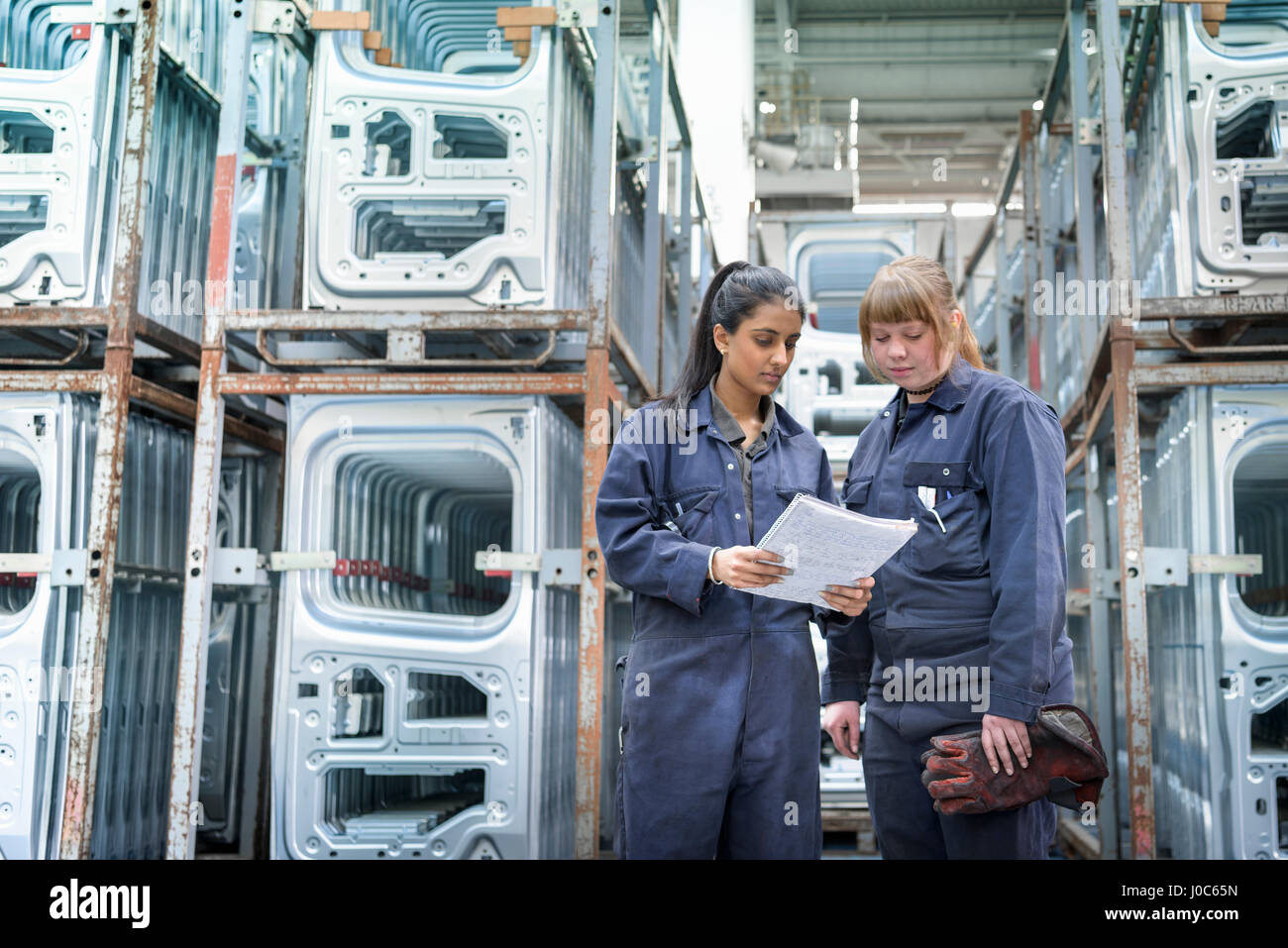 Female apprentice electrician and welder in car factory Stock Photo