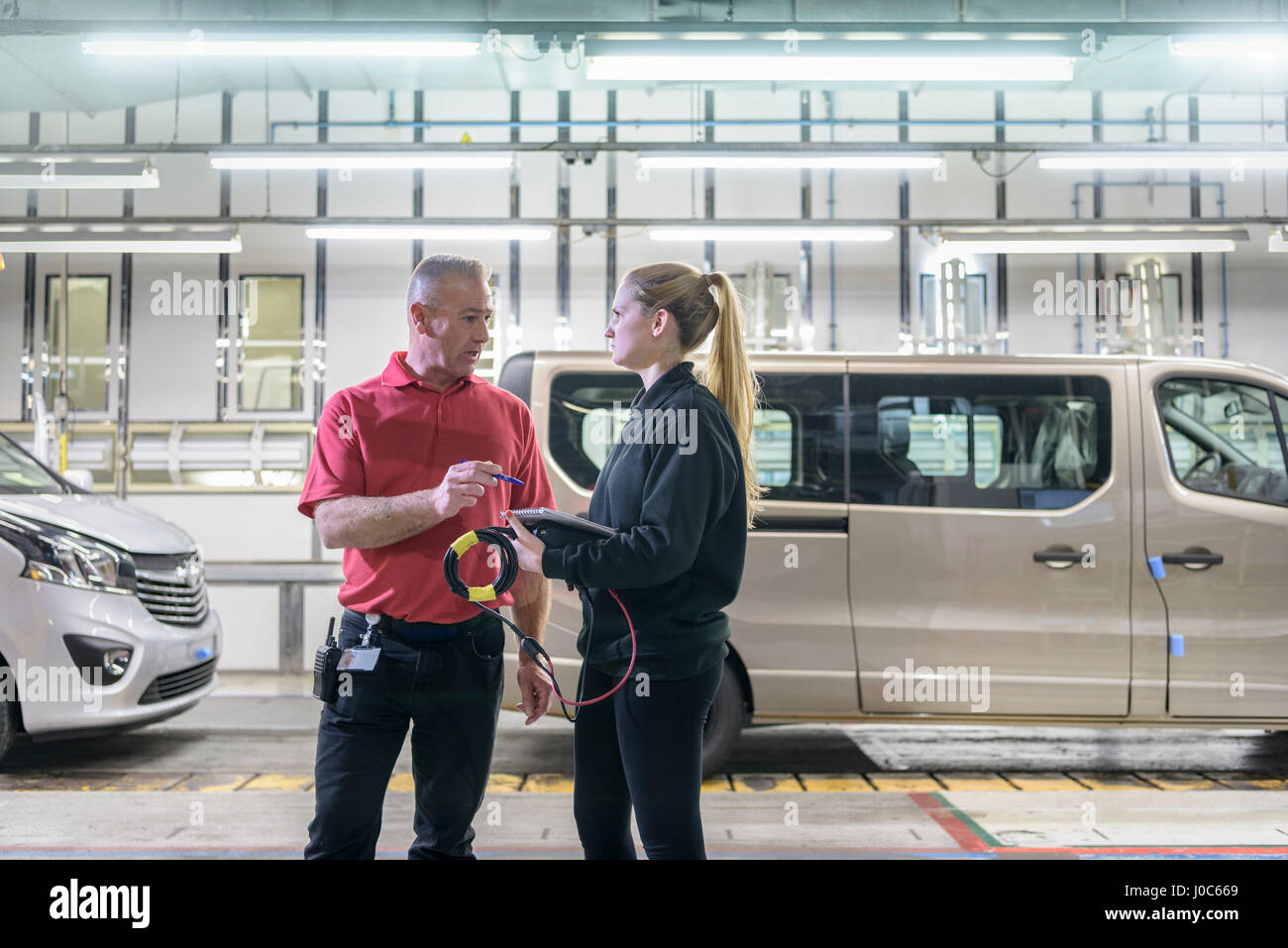 Female apprentice engineer with mentor on production line in car factory Stock Photo