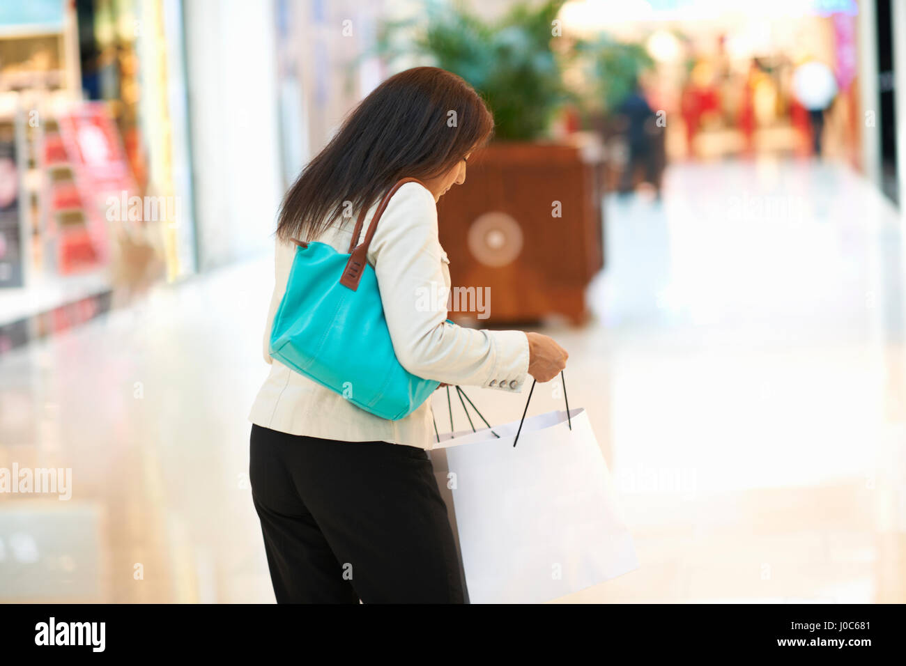 Mature woman looking at her shopping bag in shopping mall, Dubai, United Arab Emirates Stock Photo