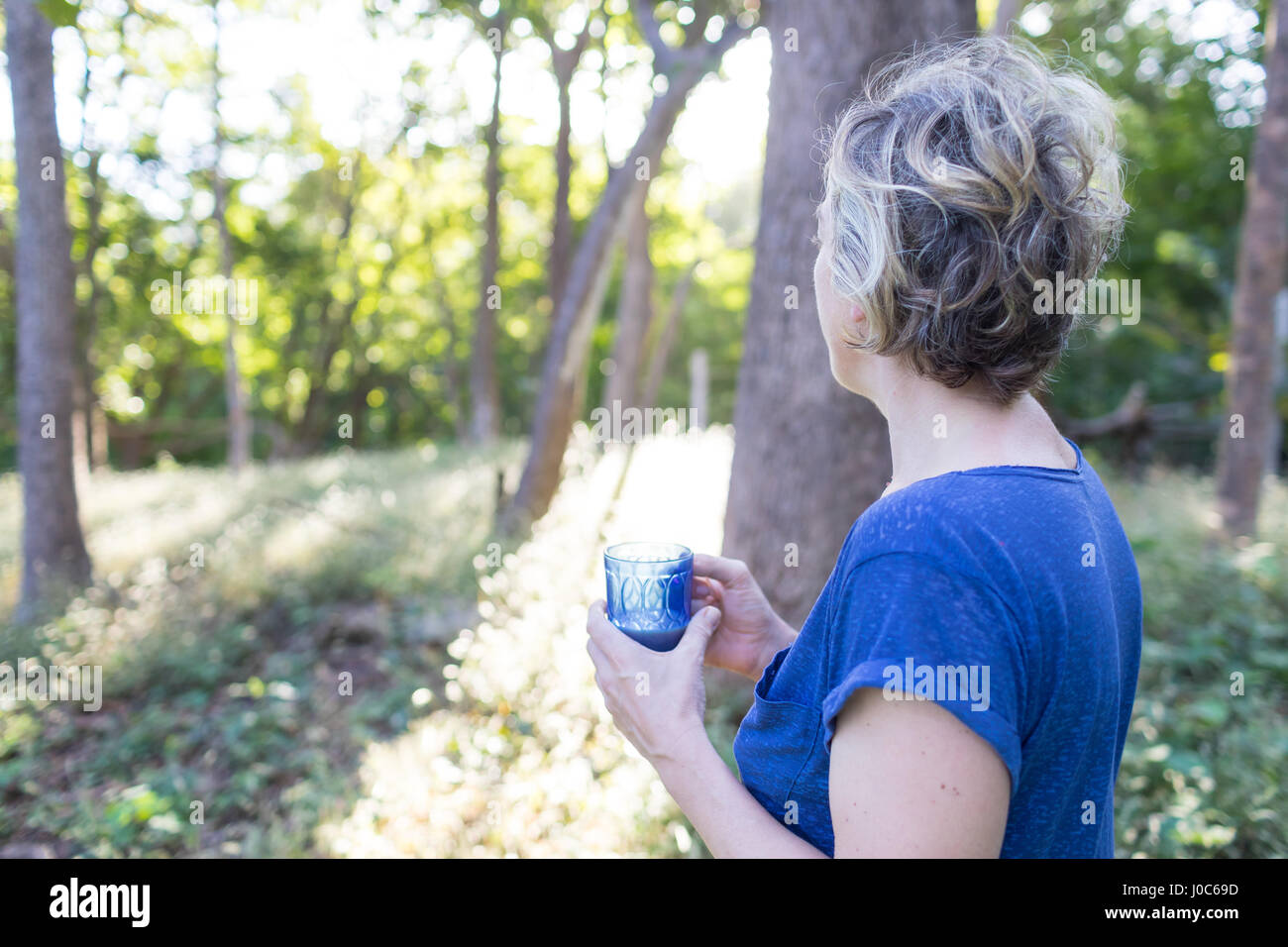Mature woman with drink looking out at rainforest, Nosara, Guanacaste Province, Costa Rica Stock Photo