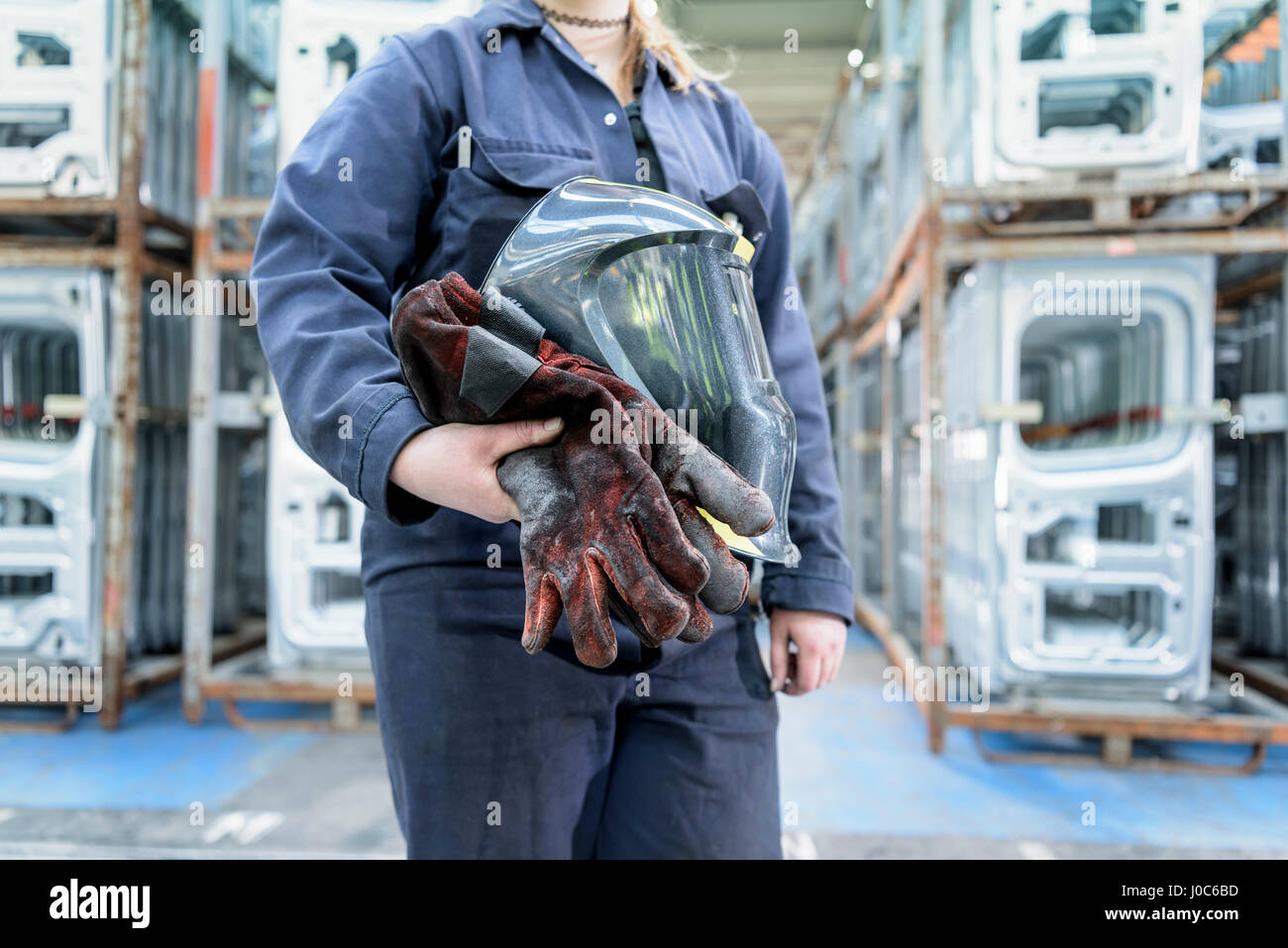 Female apprentice welder holding equipment in car factory Stock Photo
