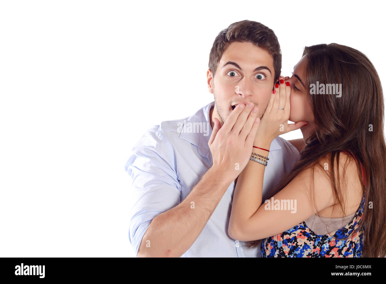 Portrait of a young woman whispering secret to her boyfriend. Isolated white background. Stock Photo