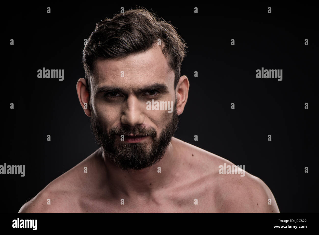 Portrait of young handsome bearded man looking at camera on black Stock ...
