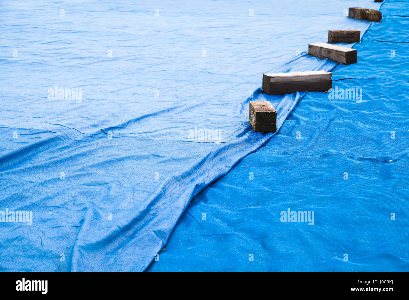 Blue industrial mesh textile with wooben planks covers ground area under construction Stock Photo