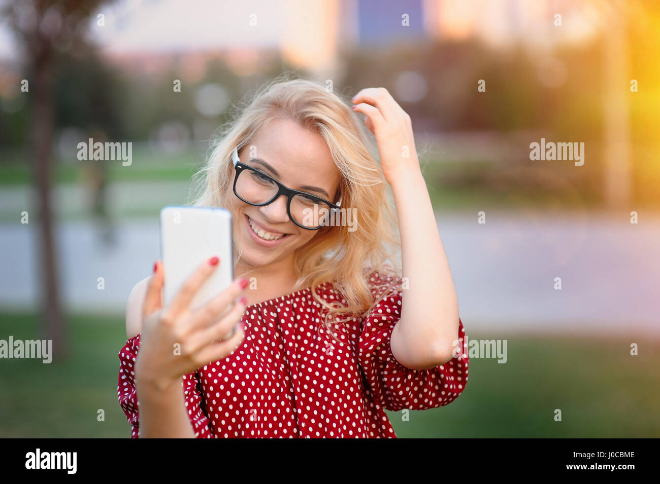 Smiling young woman in glasses with the phone outdoors Stock Photo