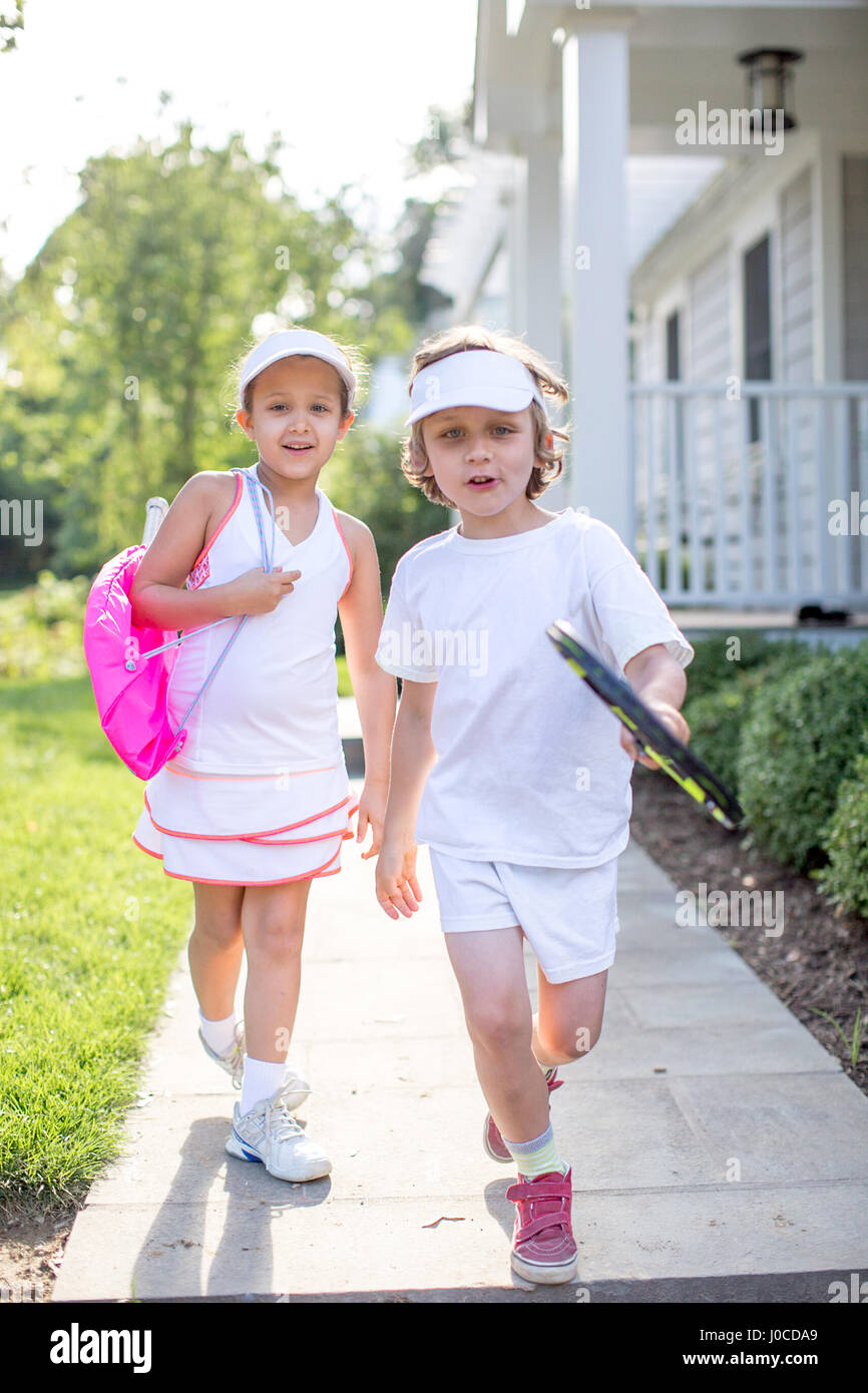 Portrait of boy and girl tennis players on garden path Stock Photo