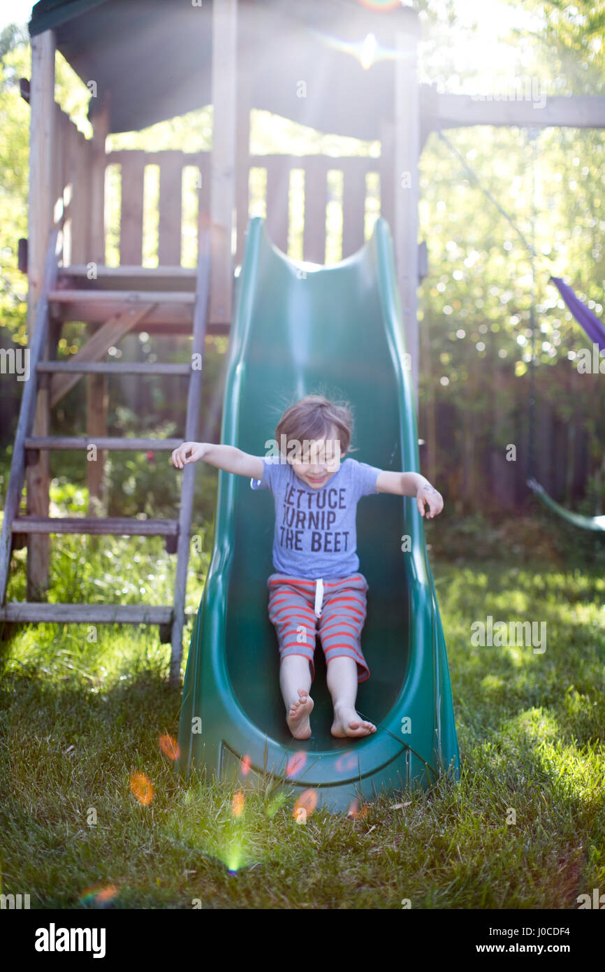 Boy sliding down garden slide Stock Photo