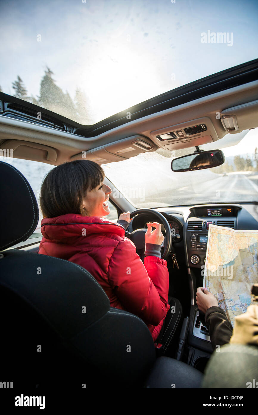 Woman driving car, friend in passenger seat looking at map Stock Photo