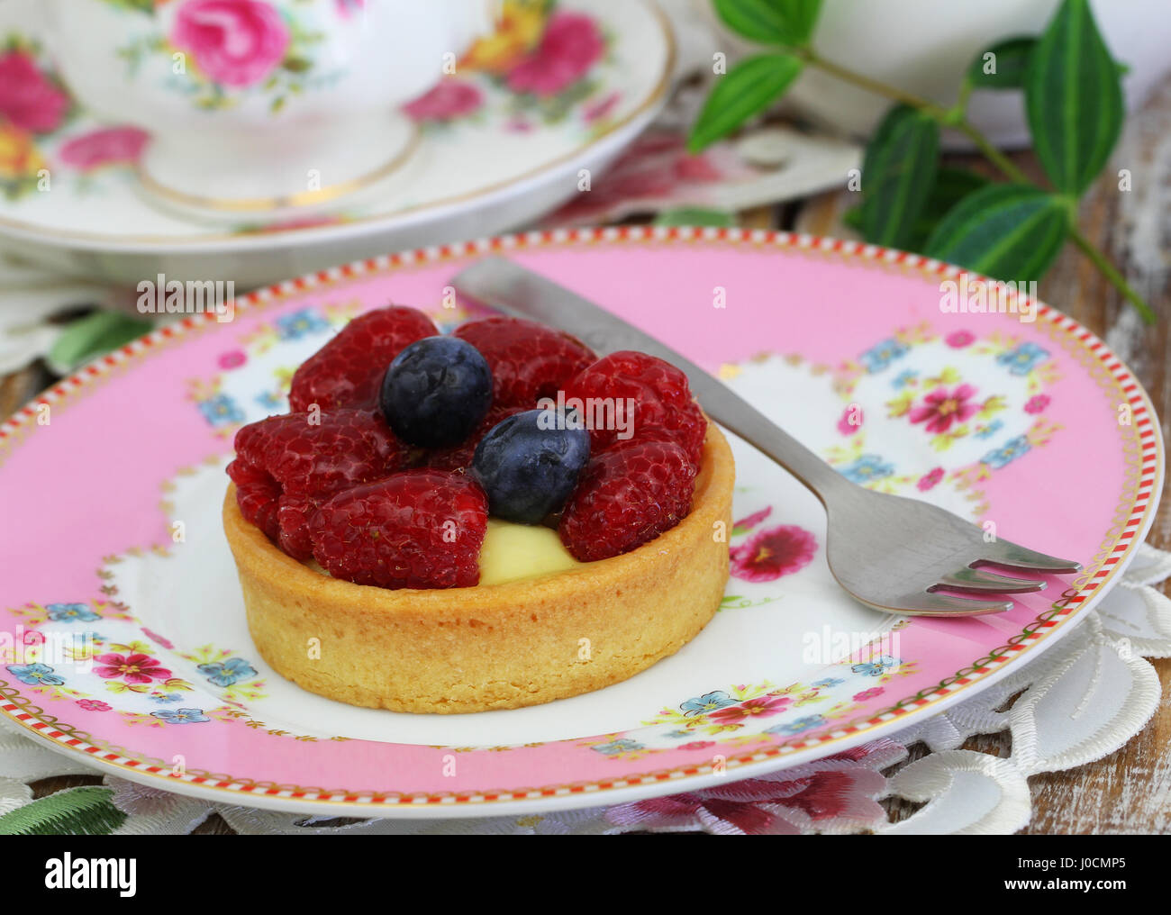 Cream cake on crunchy base with raspberries and blueberries on vintage plate, closeup Stock Photo