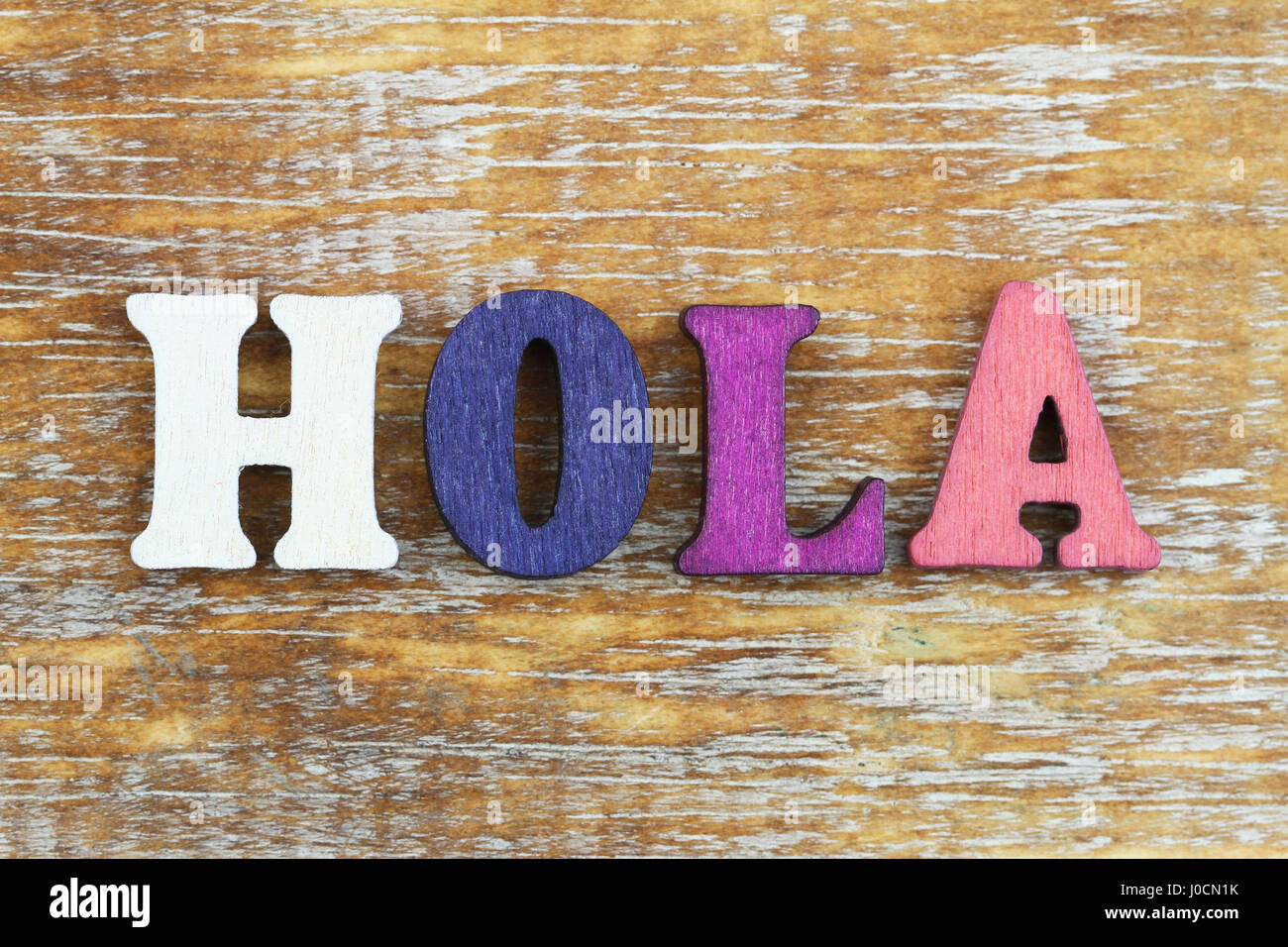 Word hola (hello in Spanish) written with colorful letters on wooden surface Stock Photo