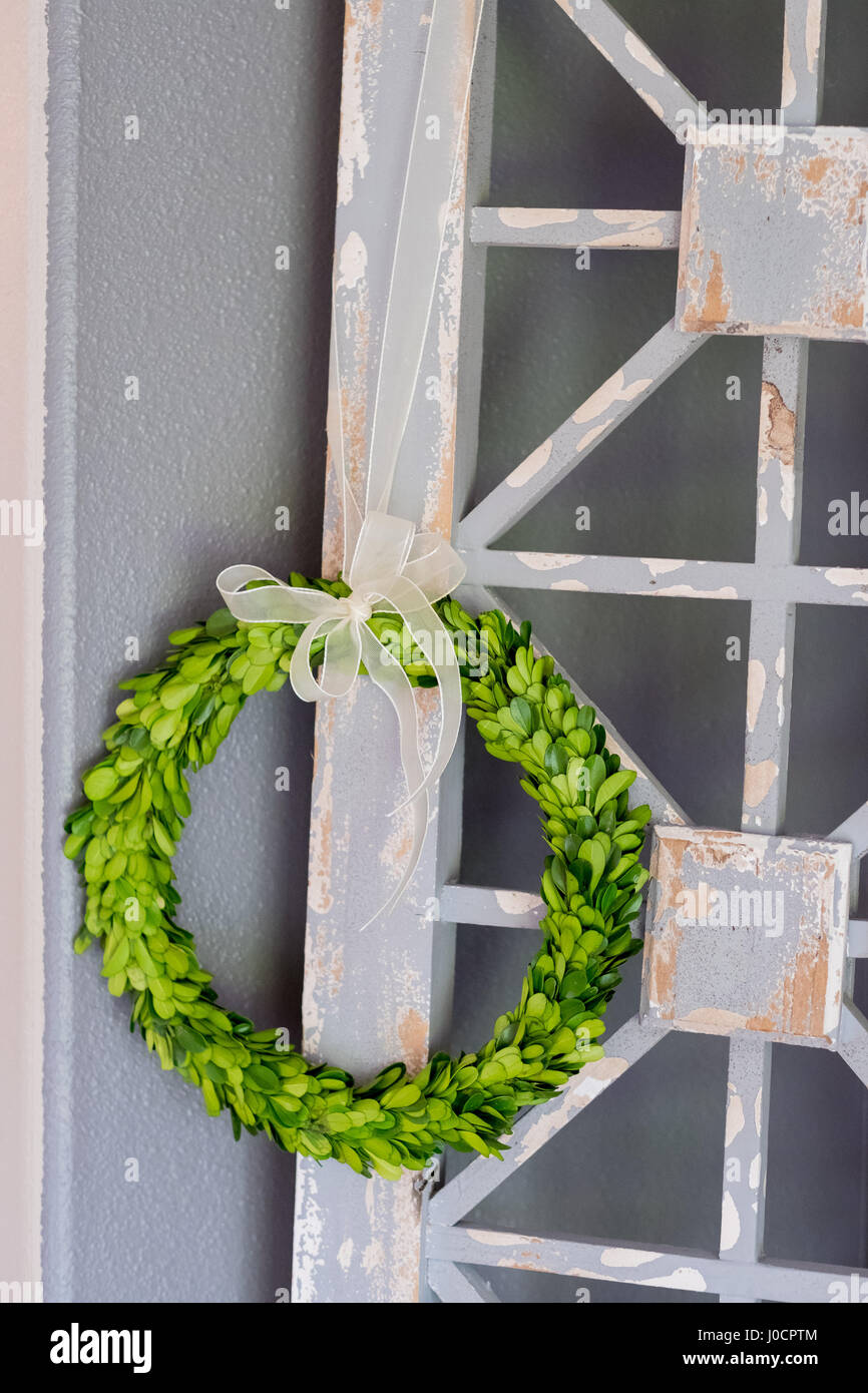 Green wreath used to decorate a country home on a rustic piece of wood. Stock Photo
