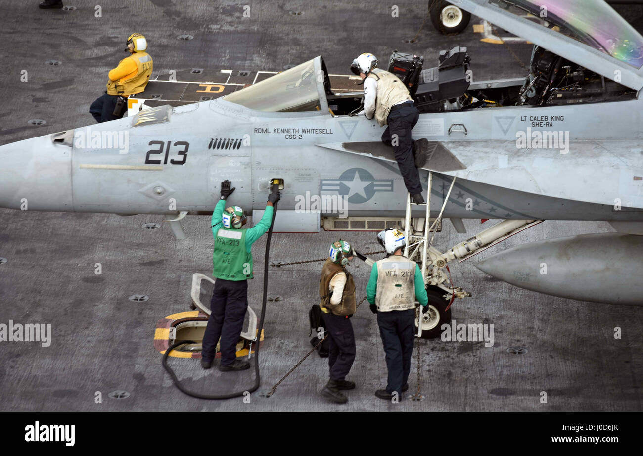 U.S. Navy sailors service a F/A-18F Super Hornet fighter aircraft attached to the 'Blacklions' of the Strike Fighter Squadron 213 on the flight deck of the Nimitz-class aircraft carrier USS George H.W. Bush April 8, 2017 in the Arabian Gulf. The aircraft carrier is deployed in Operation Inherent Resolve against the Islamic State in Iraq and Syria. Stock Photo