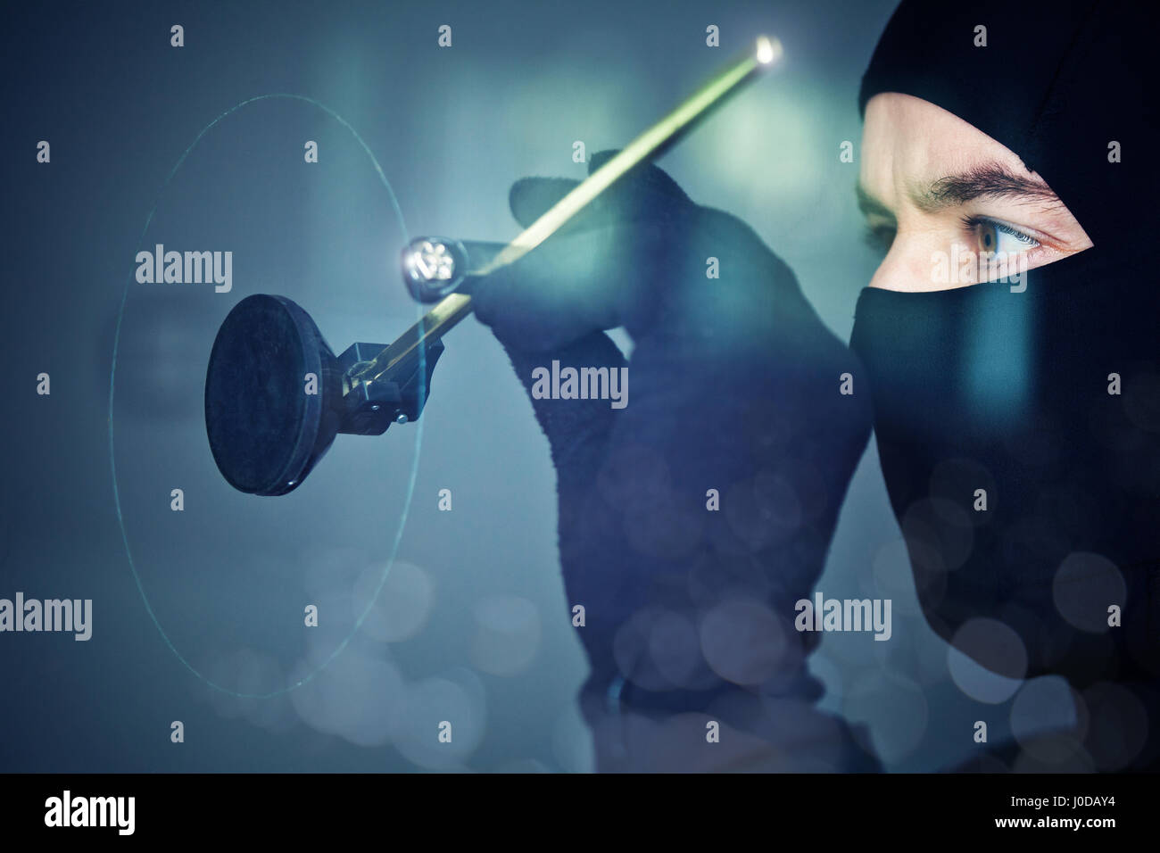 burglar with balaclava use circular glass cutter Stock Photo