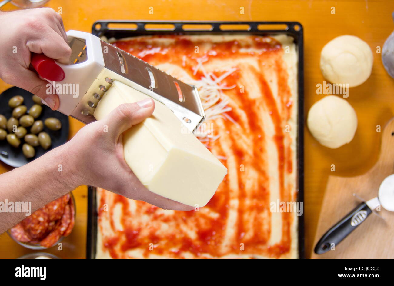 Man grating cheese on a pizza base. Making pizza Stock Photo