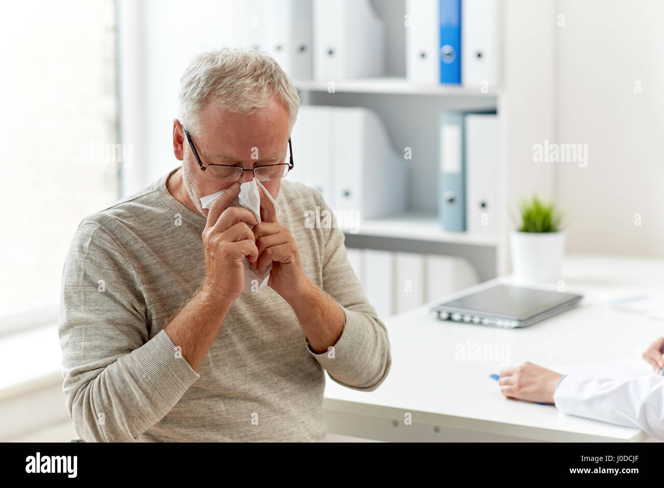 senior man blowing nose with napkin at hospital Stock Photo