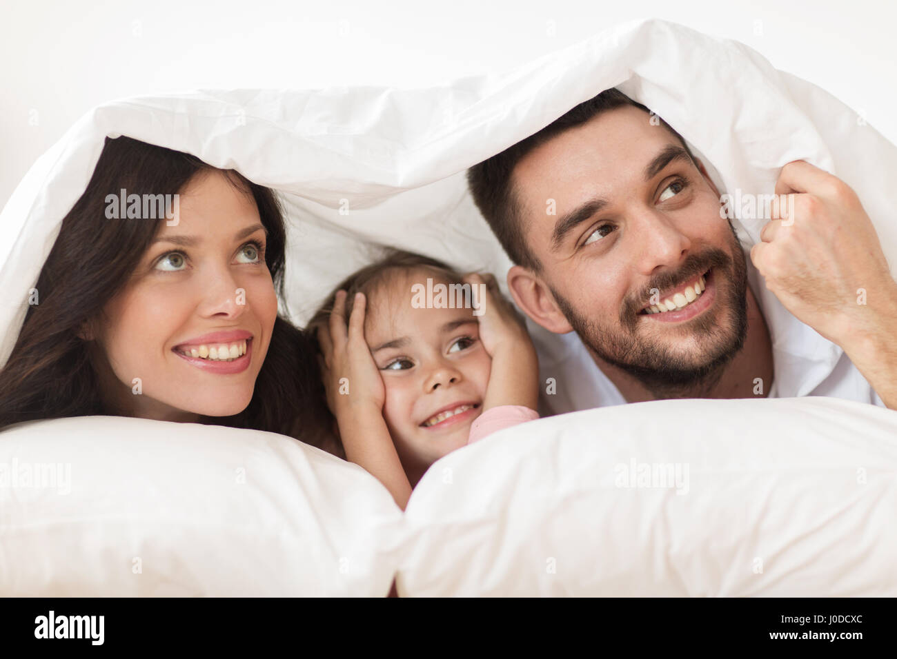 happy family lying in bed under blanket at home Stock Photo Alamy