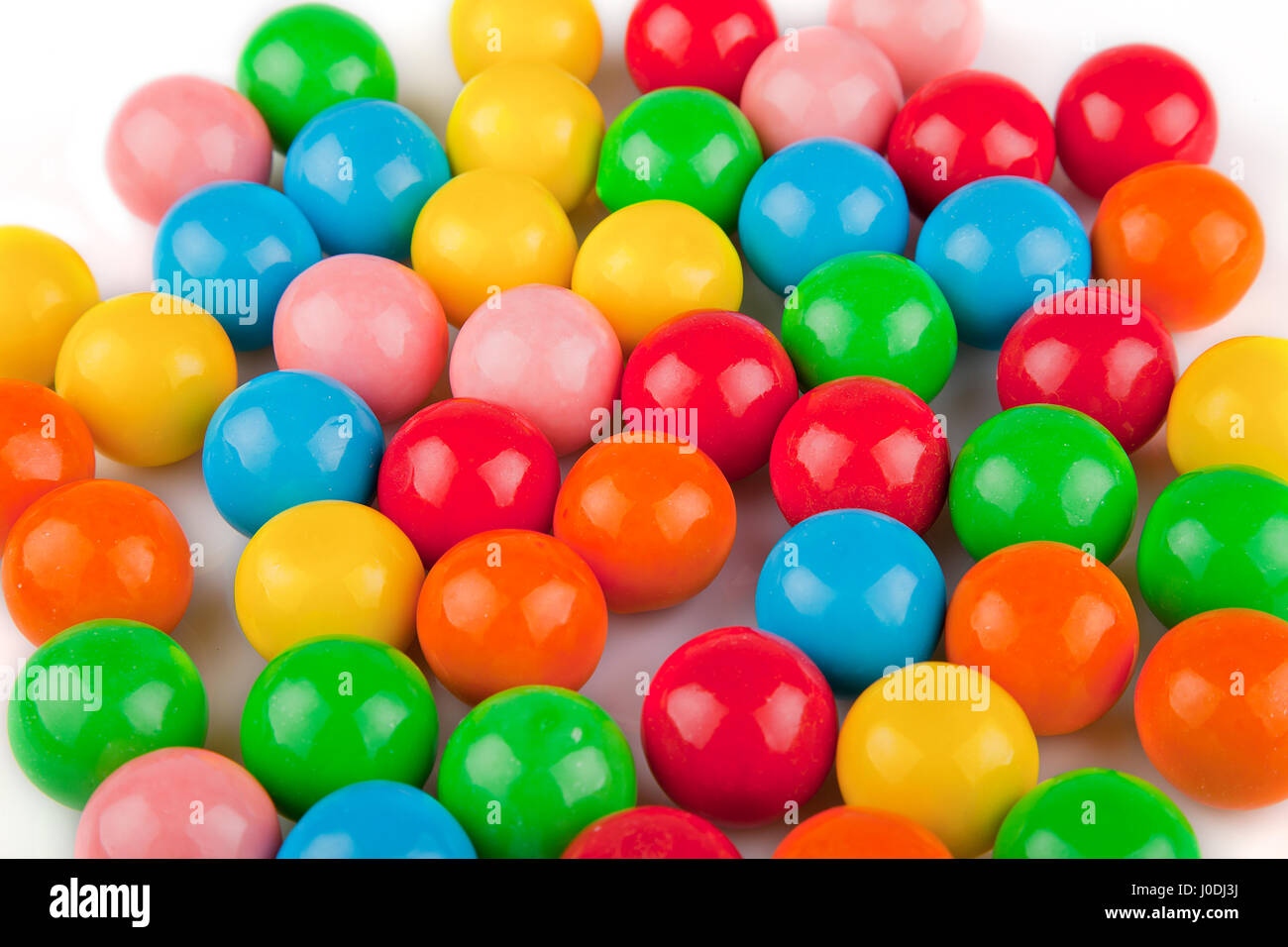 Multicolored gumballs on a white surface. Bubble gums isolated on white background. Stock Photo