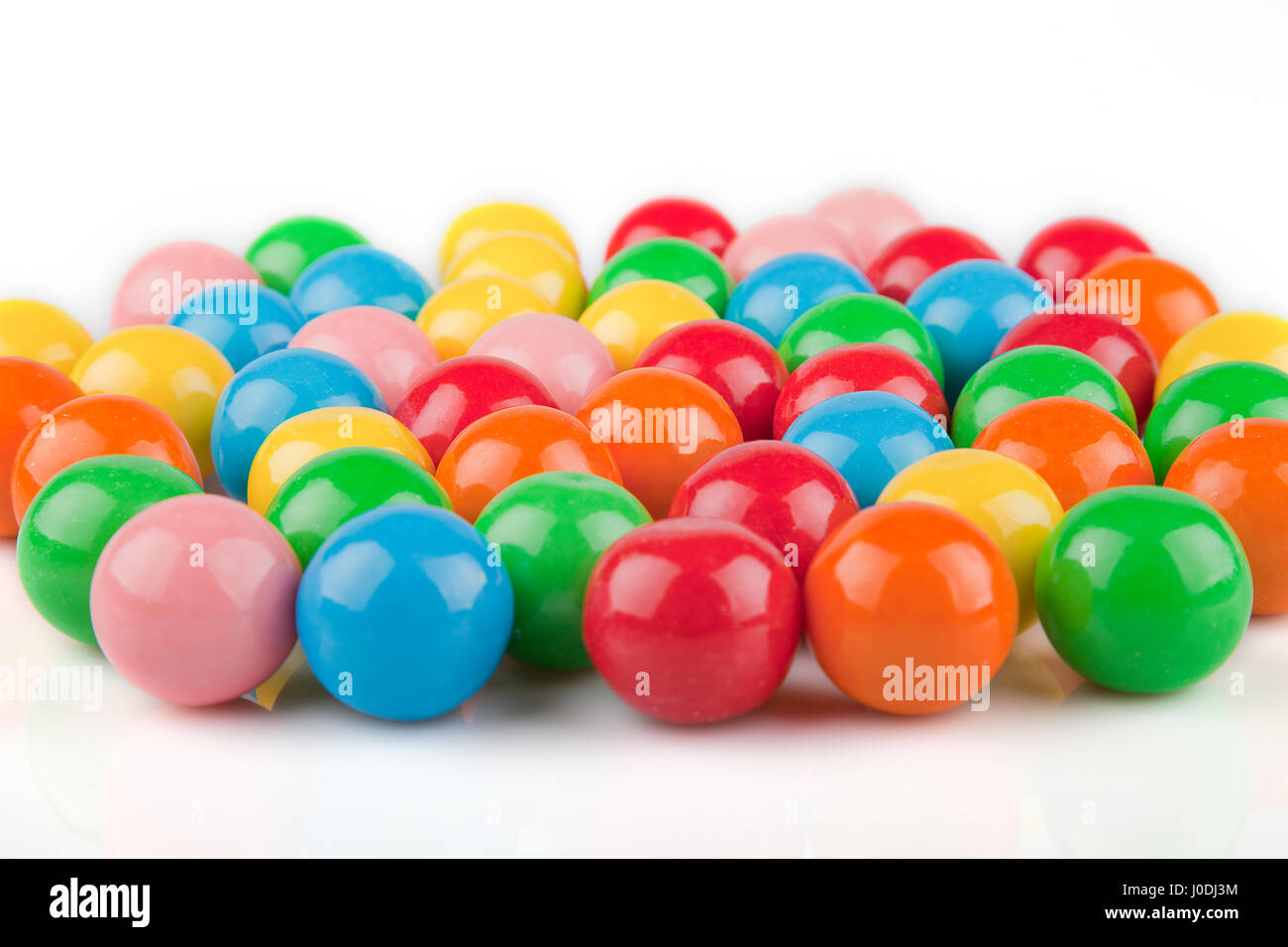 Multicolored gumballs on a white surface. Bubble gums isolated on white background. Stock Photo