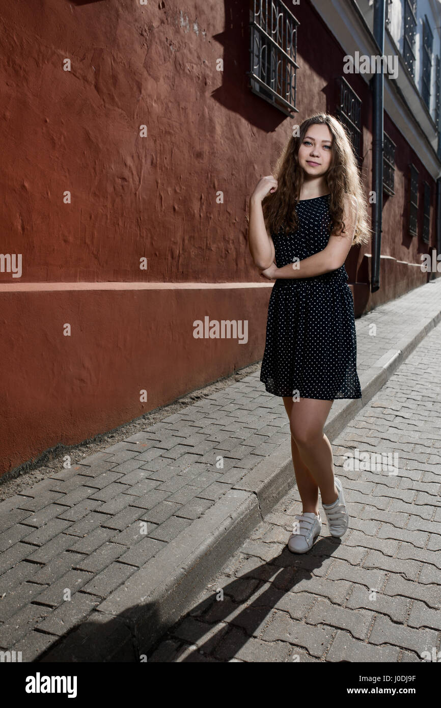 Beautiful brunette young woman wearing dress and walking on the street ...