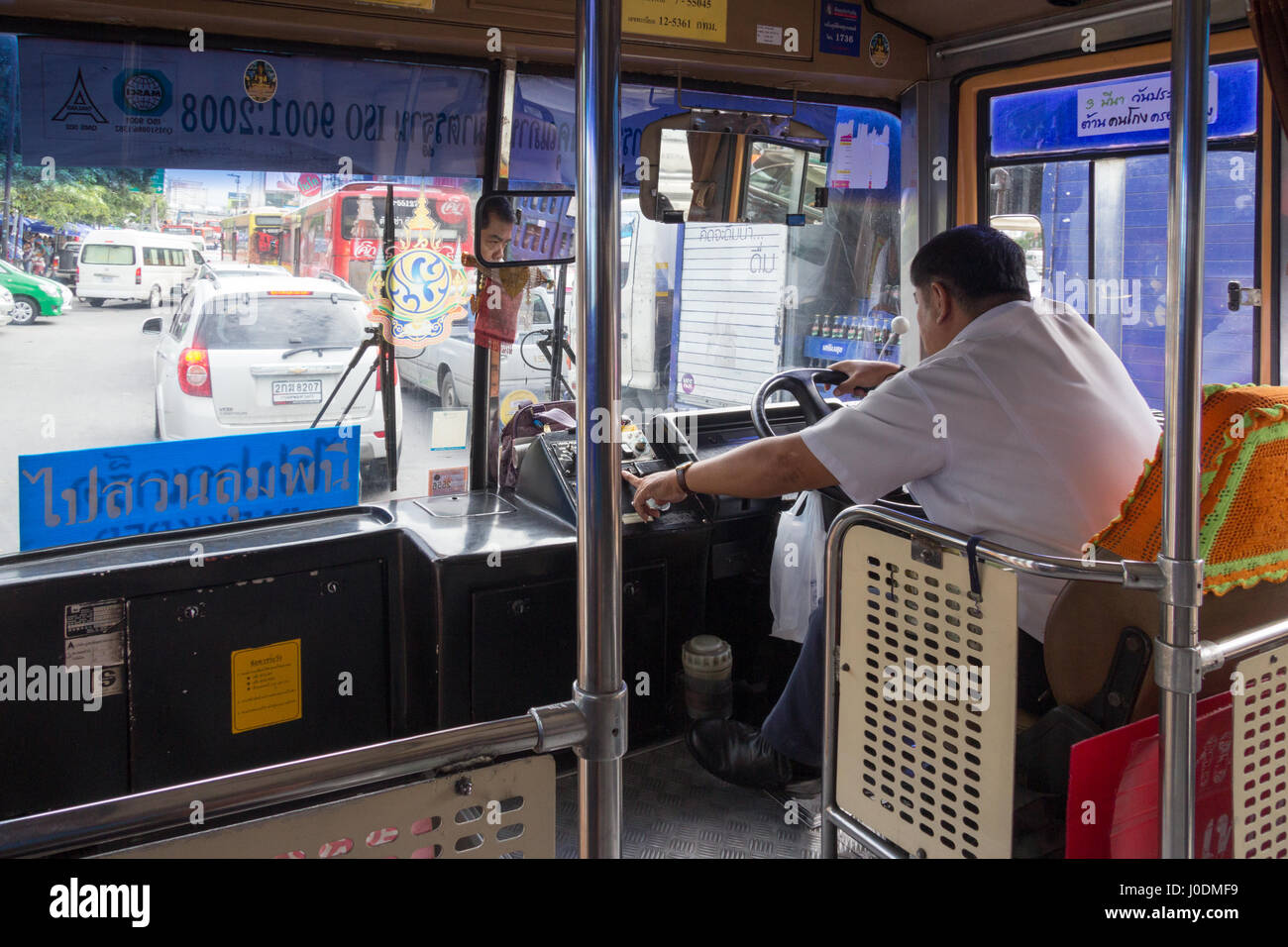 Thai bus driver negotiating traffic in Bangkok, Thailand Stock Photo