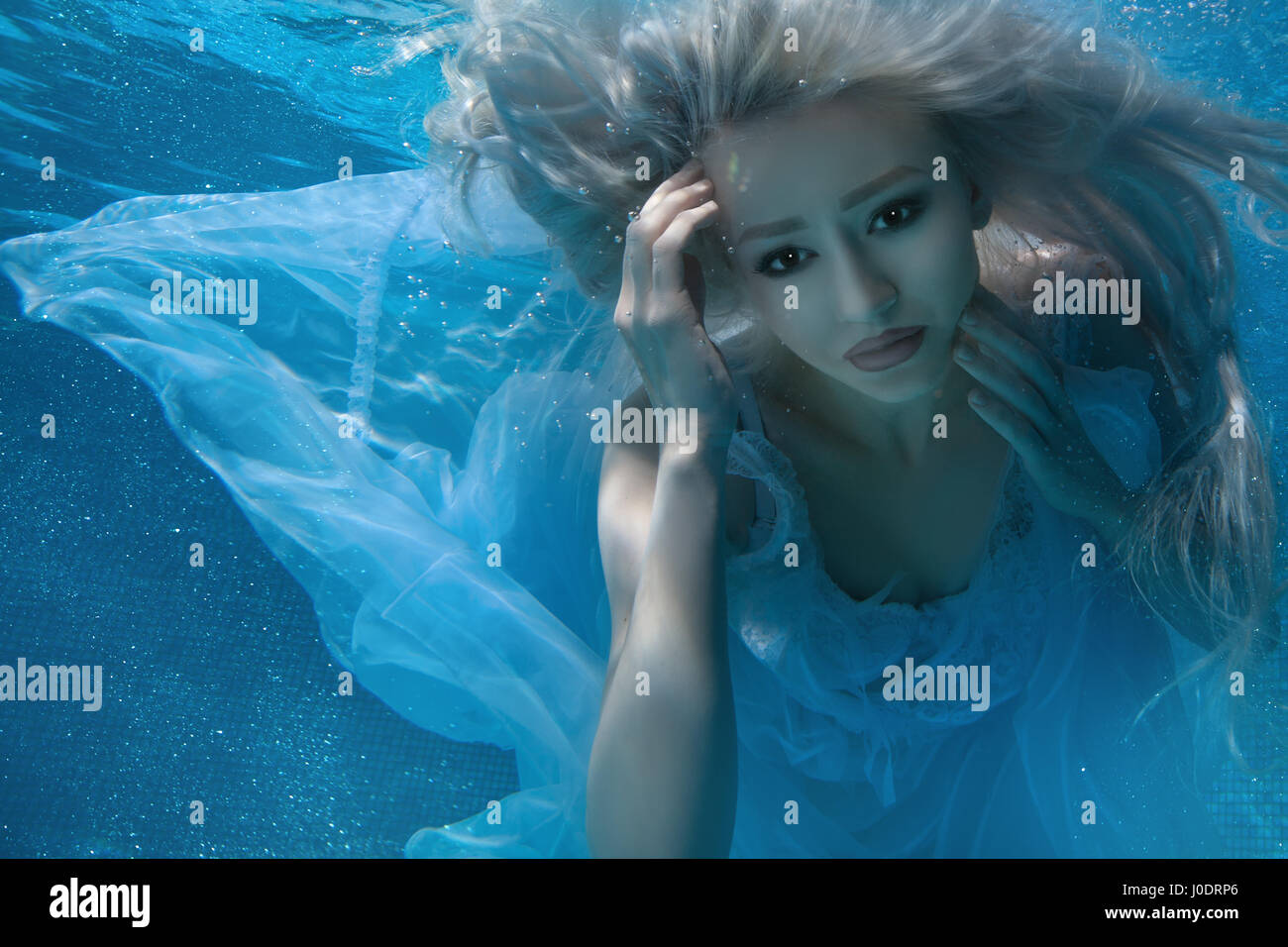 Blonde woman under water, her long hair and a white dress. Stock Photo