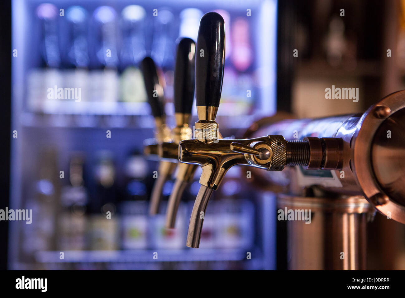 Lot of vintage Golden beer taps in a bar with a fridge of bottles in